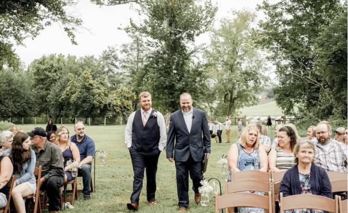 Newlyweds looking at sunset posing on hill